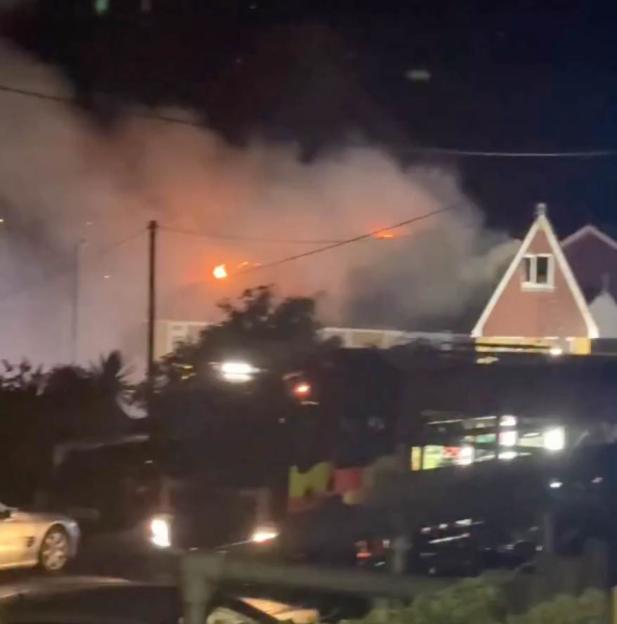 Firefighters extinguishing a house roof fire with a ladder truck, following a lightning strike.