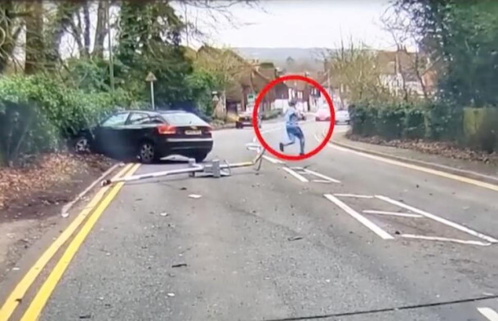 Man running away from a car crash on a street.