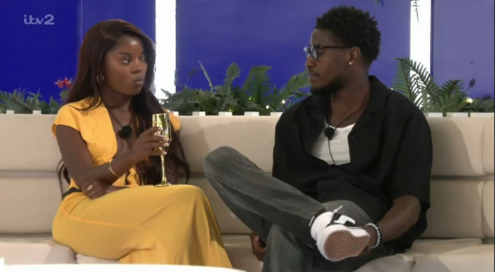 Two people sitting on a couch, facing each other.