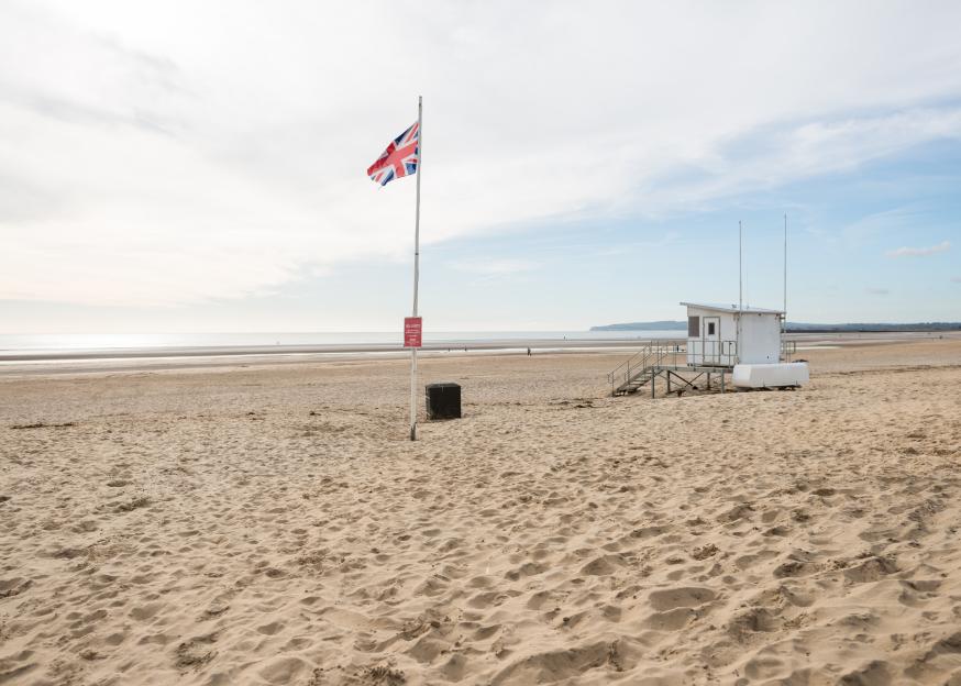 Lifeguard hut and Union Jack flag on a sandy beach.