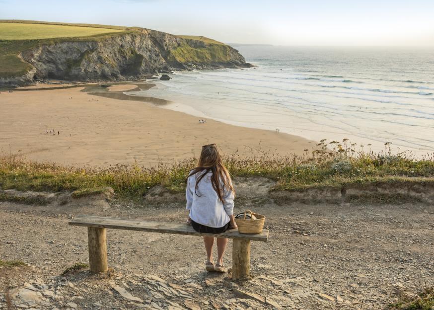 A woman sits on a bench overlooking Sun Haven Holiday Park beach.