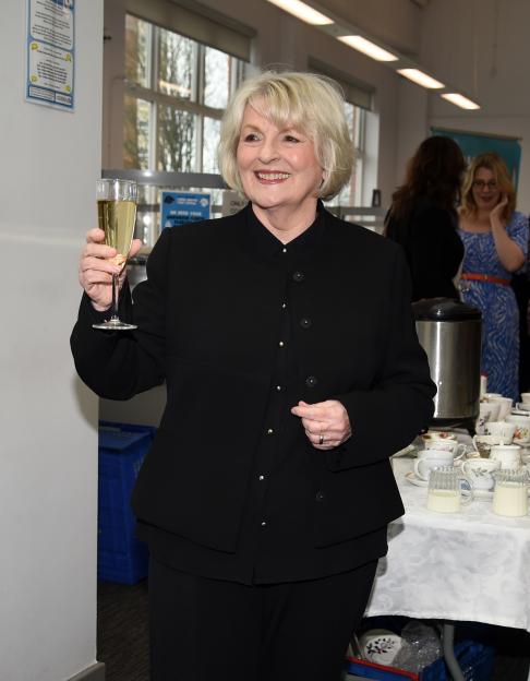Brenda Blethyn holding a glass of champagne at a ceremony.