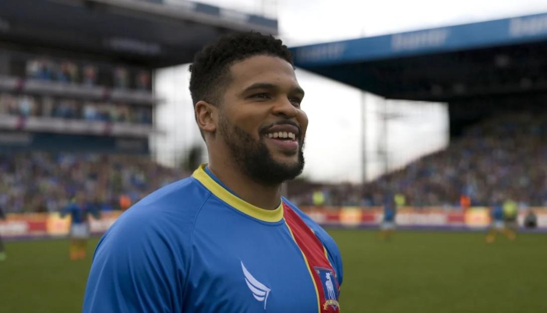 Kola Bokinni as Isaac McAdoo smiling in his AFC Richmond jersey.