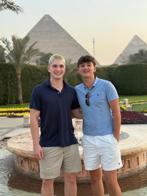 Two young men standing in front of the pyramids of Giza, Egypt.