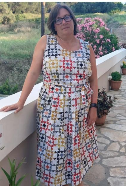 Justine Leader in a patterned dress, standing outdoors.
