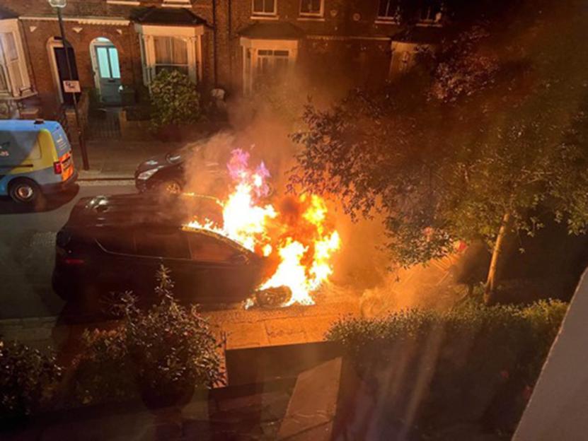 A Toyota Rav4 on fire in a residential street at night.