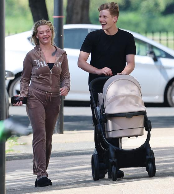 Freddy Brazier and Holly Swinburn walk together, with Freddy pushing a baby carriage.