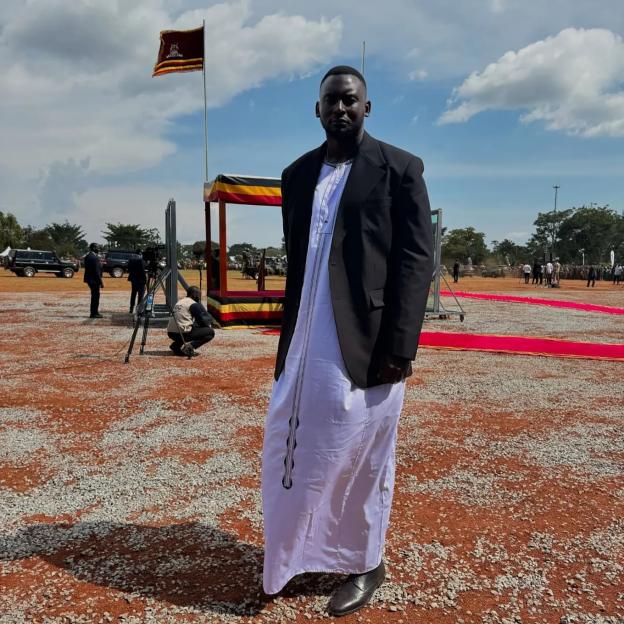 George Desmond Kamurasi wearing a traditional white tunic and black blazer.