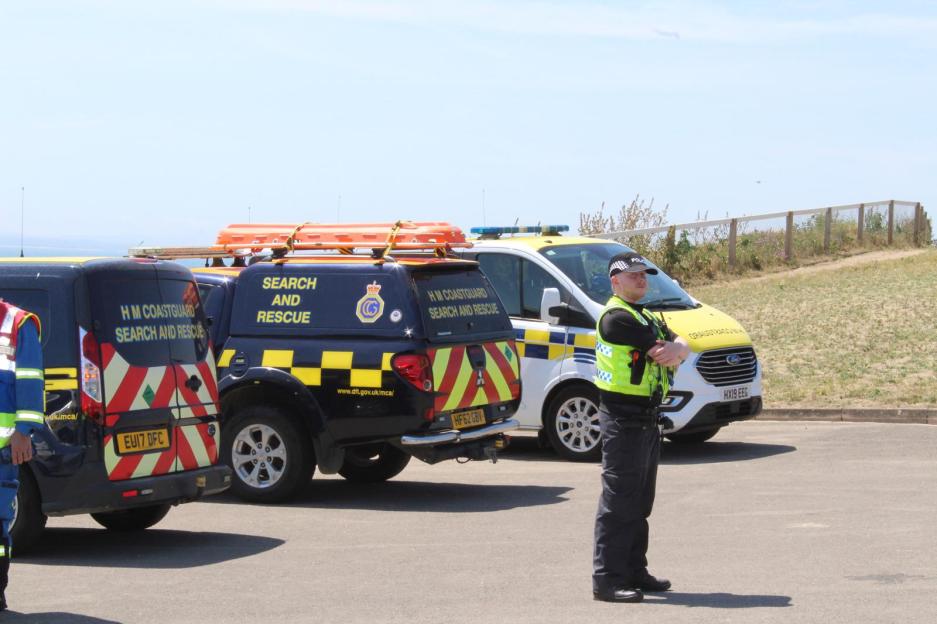 HM Coastguard Search and Rescue vehicles with a police officer.