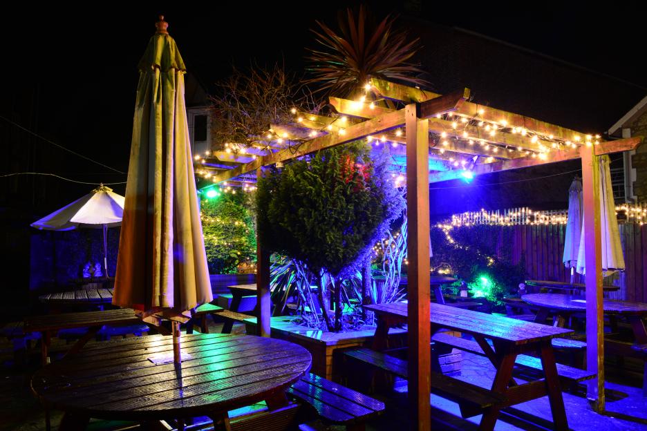 Illuminated garden seating with colorful fairy lights at night.