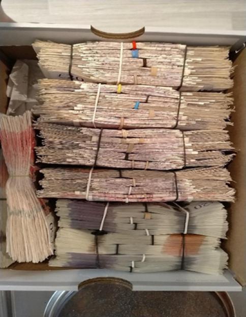 Large stacks of cash secured with rubber bands in a box.
