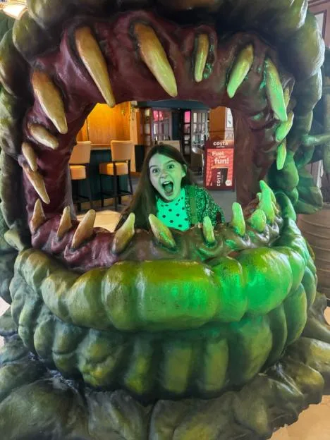 A young girl poses inside the giant, toothy jaws of a monster prop at Alton Towers Scarefest.
