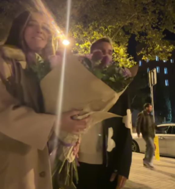 Woman and man holding a bouquet of flowers at night.