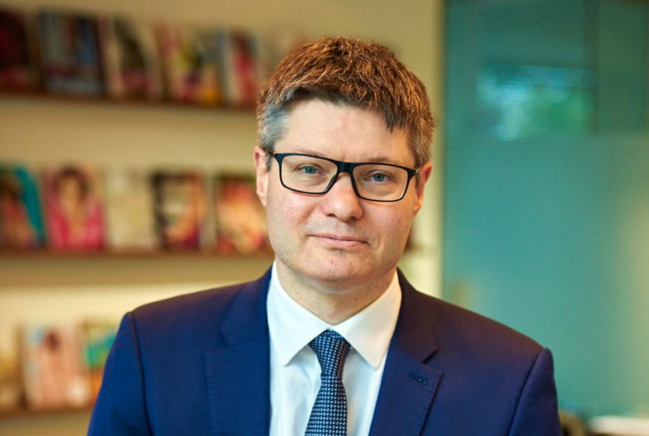 Lord Wolfson of Aspley Guise, CEO of Next, sits wearing a blue suit, white shirt, and patterned blue tie.