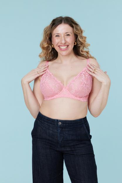 Katie Weir smiling while wearing a pink lace bra.