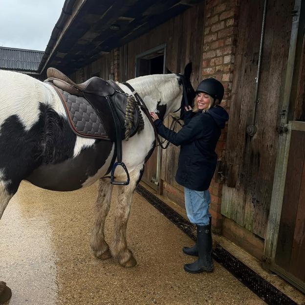 Sydney Sweeney petting a horse in a stable.