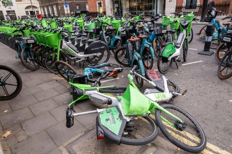 A sea of electric hire bikes, including some knocked over, parked haphazardly in a London square.