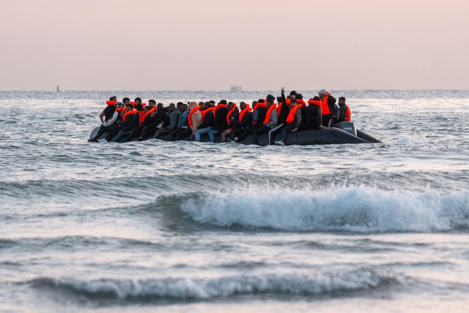 Migrants in an inflatable dinghy preparing to sail into the English Channel.