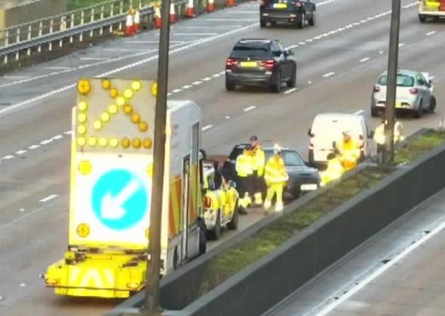 Traffic workers and vehicles on the side of a highway.
