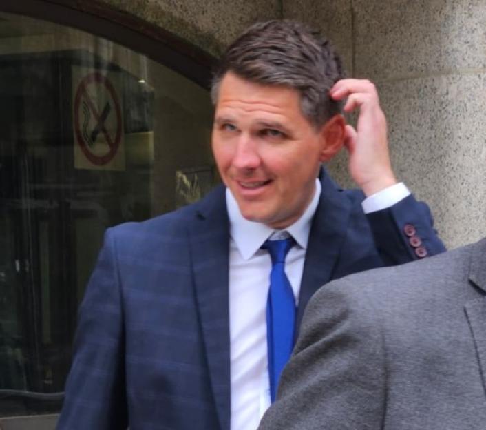 A man in a suit scratches his head.