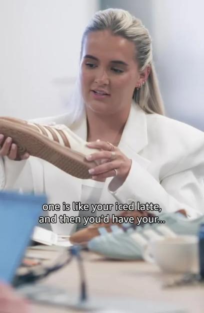 A woman in a white blazer holding a tan and white shoe.