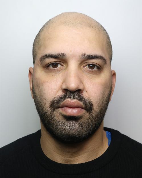 Mugshot of Amin Abedi Mofrad, a bald man with a dark beard and mustache, wearing a black top.