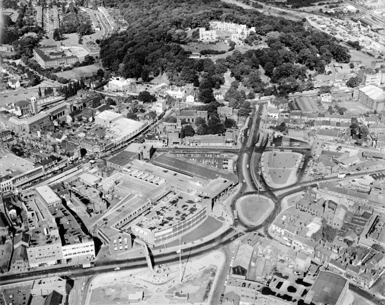 Black and white aerial view of Dudley in the West Midlands, showing the Trindle Road traffic island below and Dudley Castle in the background.