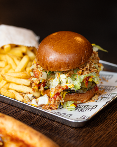 Vegan smash burger with fries on a tray.