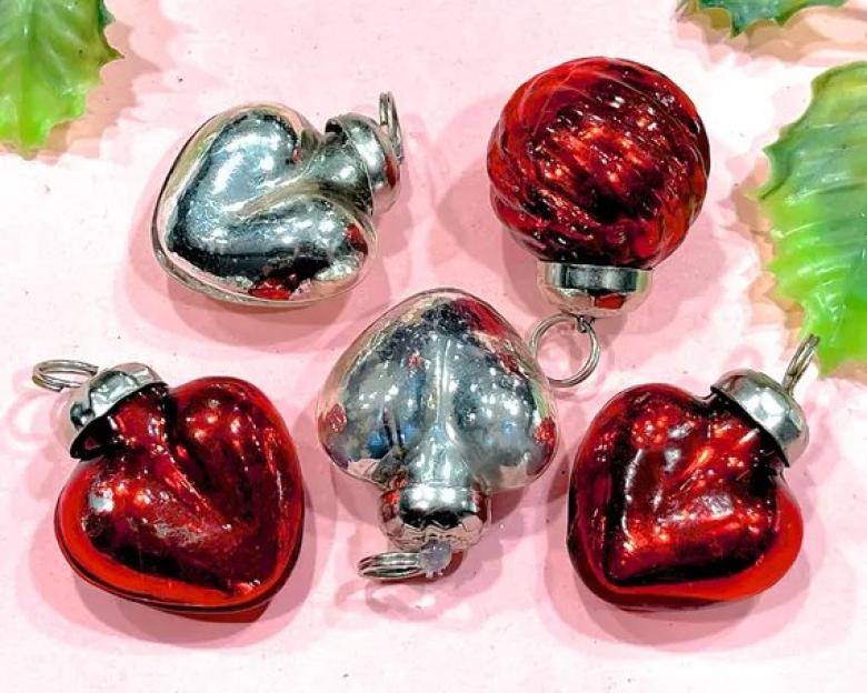 Five vintage red and silver heart-shaped and round Christmas ornaments.