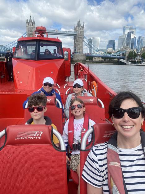 A family on a Thames Rockets boat trip with Tower Bridge and the London skyline in the background.