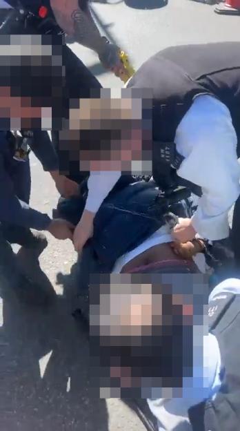 Police officers detaining a man on the ground.