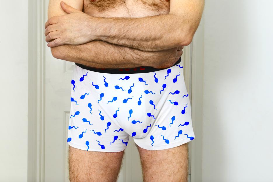 A man wearing white boxer shorts with blue sperm patterns.