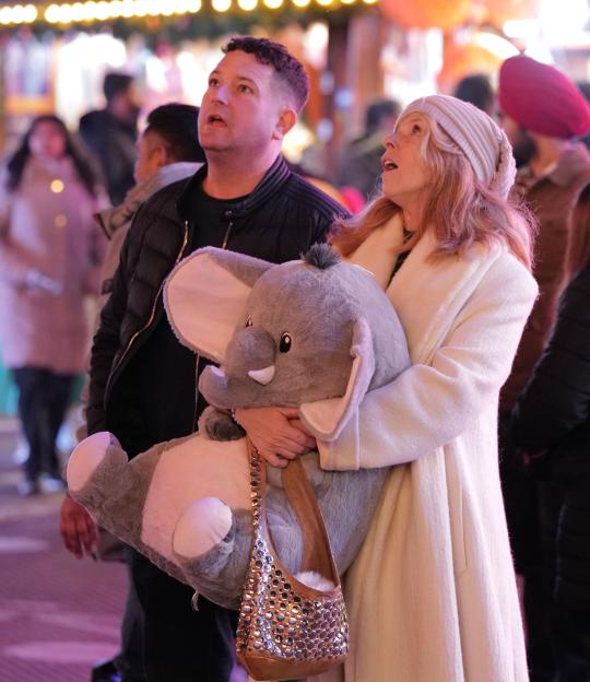 Kate Garraway holding a large stuffed elephant while looking up, with a man beside her.
