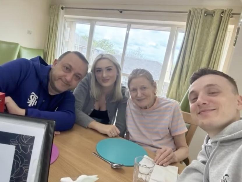 John, his wife Gilly, and their two children Andrew and Anna, pose for a photo at a table.