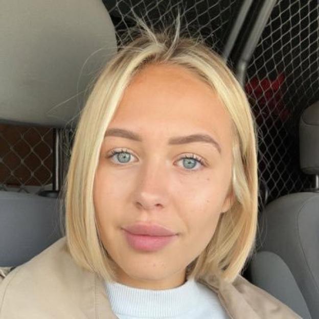 A woman with blonde hair and blue eyes looks at the camera.