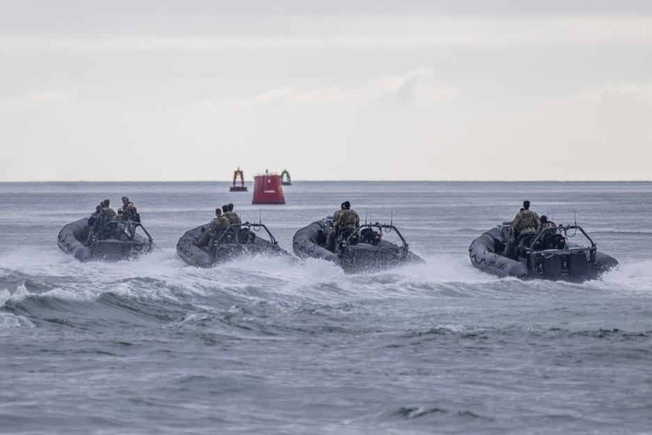 Four commandos in three gray RIBs speed across the water during a Special Boat Service training exercise.