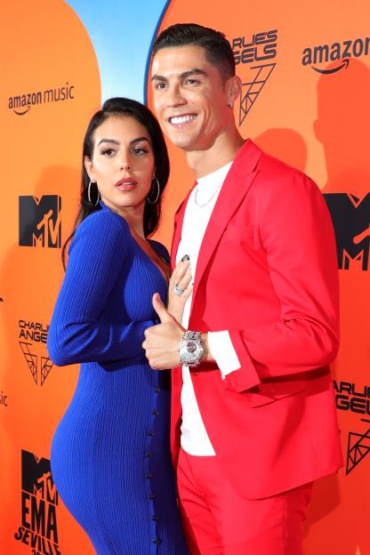 Georgina Rodriguez in a blue dress and Cristiano Ronaldo in a red suit posing at the MTV EMAs 2019.