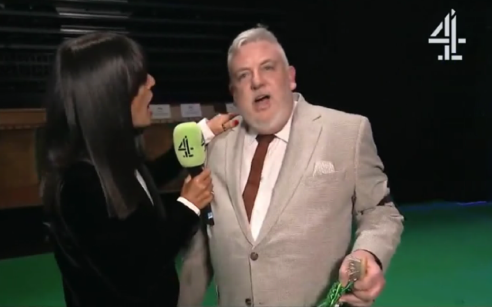 A woman holding a microphone to a man accidentally hits her face with it.