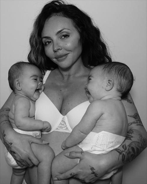 Jesy Nelson cradles two babies, smiling into the camera.
