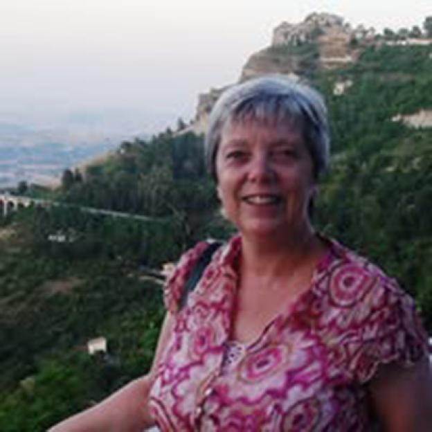 Jane Kelvey smiling with a mountainous landscape behind her.