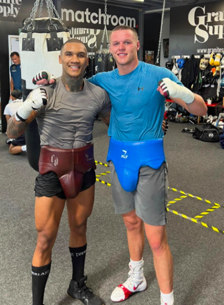 Two boxers smiling and posing in a gym.