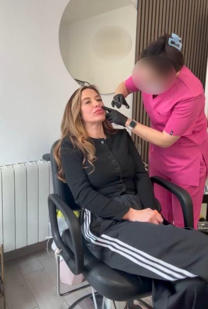 A woman getting lip injections from a person in pink scrubs.