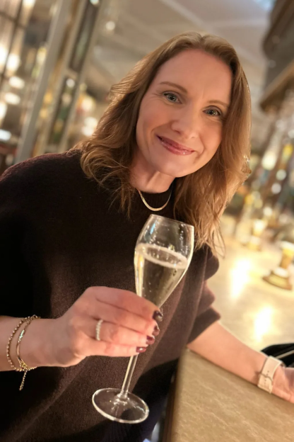 A woman smiling and holding a glass of champagne.