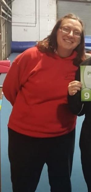 Justine Leader smiling, wearing a red sweatshirt and black pants.
