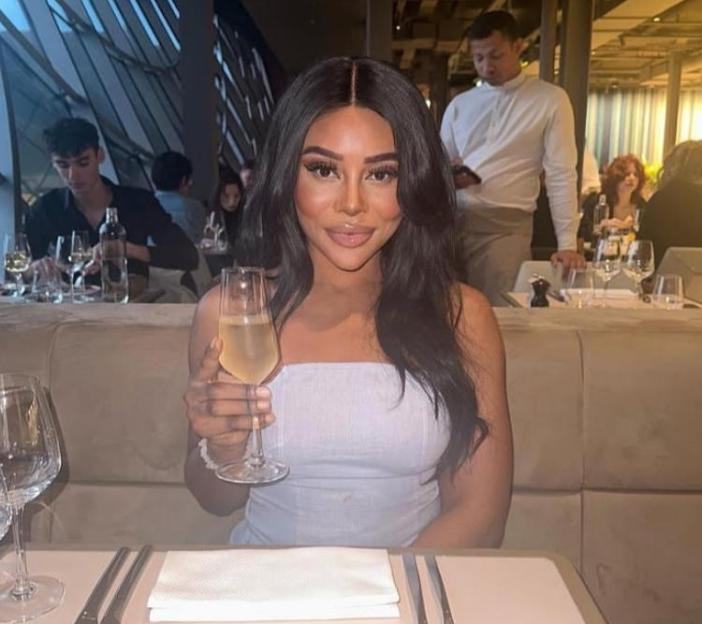 A woman smiling and holding a glass of champagne at a restaurant.
