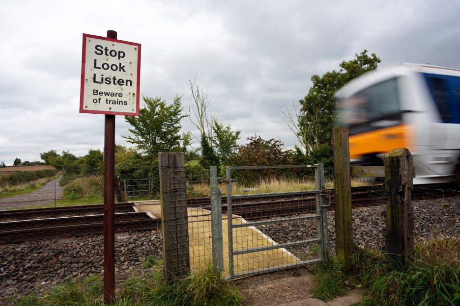 Chiltern Railways passenger train passing a rural pedestrian level crossing in Claydon, Banbury, Oxfordshire, UK.