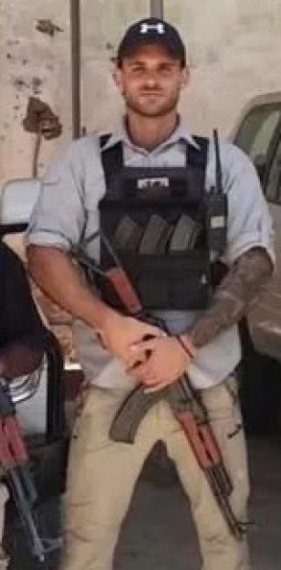 Grant Gale, wearing a tactical vest and holding a rifle, standing with three other men also in tactical gear and holding rifles.