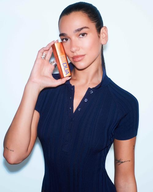 Dua Lipa holds a bottle of her "Dua" branded skincare line.