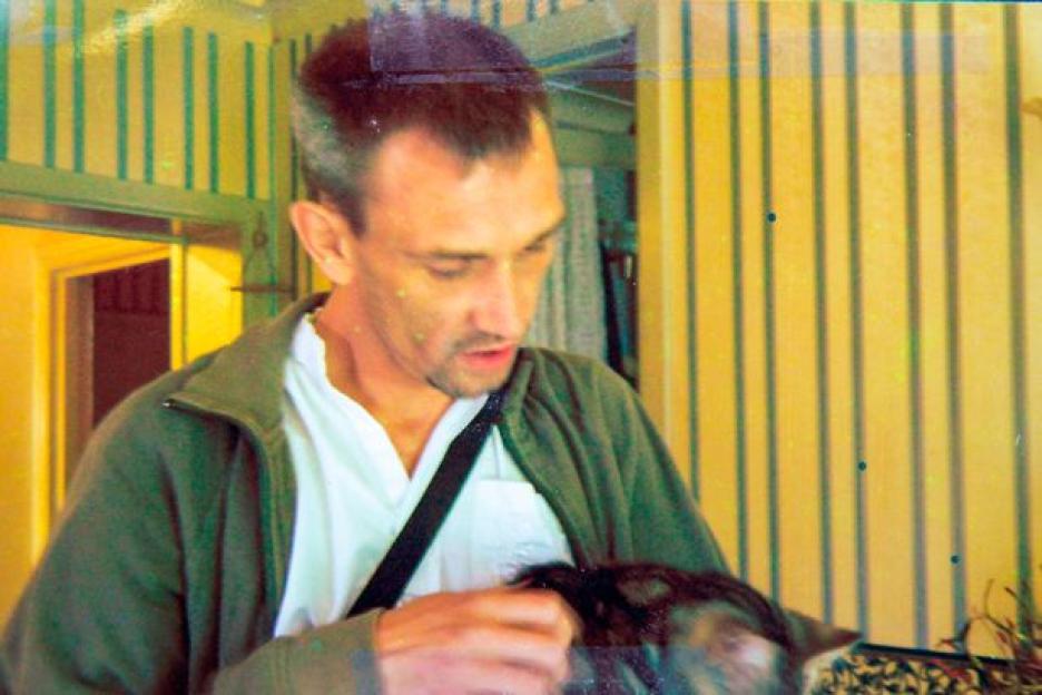 Shaun Dallison in a green jacket and white shirt, holding a dark-colored animal.