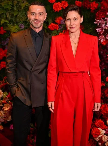 Matt Willis and Emma Willis pose together in front of a floral backdrop at an event.